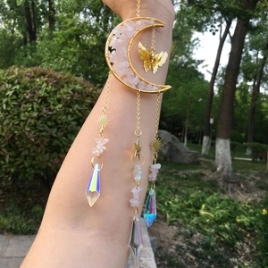 Macro shot of gold wire moon pendant filled with pink quartz and prism crystal suncatcher