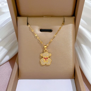 Détail d'un collier ours doré avec cœur rouge et cristaux dans un coffret cadeau