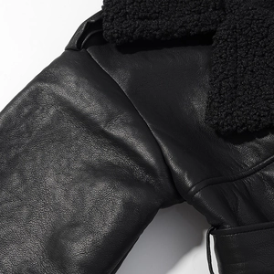 Close-up of premium black faux shearling coat detail showing leather texture and soft fur collar