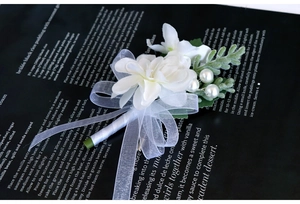 Detail of white satin rose boutonniere with pearls and ribbons for wedding suits