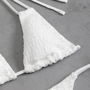 Detail of white crochet floral lace fabric and delicate tie straps for a beach bikini set