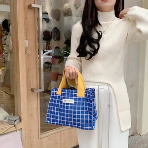 Detail of blue and white checkered canvas lunch bag with yellow handles and tag