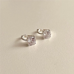 Macro shot of silver stud earrings featuring four-prong set round white zircon stones