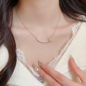 Close-up of 18k gold plated butterfly necklace with small pearls on elegant model wear