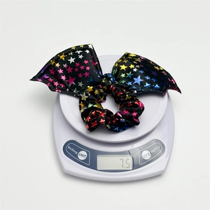 Detailed view of black bat wing scrunchie with star pattern weighing 7.5g on a scale