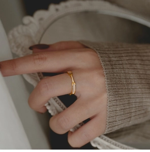 Detail van een roségouden ring met micro-zetting en parelmoer aan een vinger