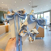 Detail of light blue sequin bow hair clips held by hand in a cozy indoor setting