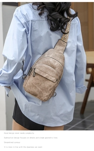 Detail of stylish beige crossbody chest bag with decorative geometric woven strap on model