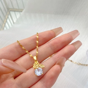 Detalle de collar con colgante de rosa dorada y una piedra de circonita redonda brillante