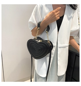 Detail der schwarzen herzförmigen Handtasche mit 3D-Prägung und goldener Kette