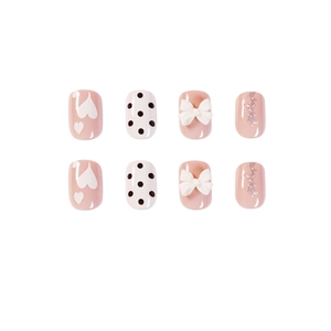 Roze en witte kunstnagels met 3D-strikjes, stippen en glitters in een korte ronde vorm