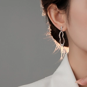 Close-up of asymmetrical silver lava hoop earrings worn by model in a minimalist style