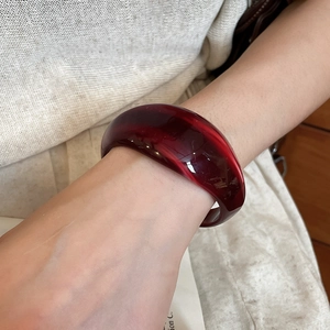 Detailed close-up of thick translucent dark red acrylic bangle worn on a model's wrist