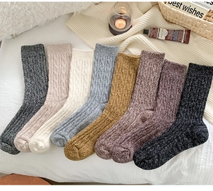 Flat lay of thick wool blend crew socks in various colors with cozy home accessories