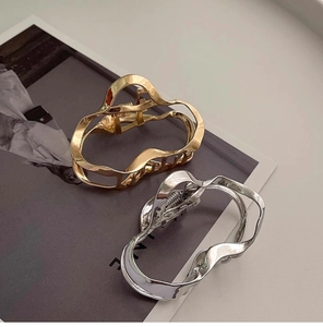 Detailed view of silver and gold liquid metal cloud hair claws on fashion magazine