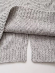 Détail de la fente latérale et de l'ourlet en maille côtelée sur un gilet gris sans manches