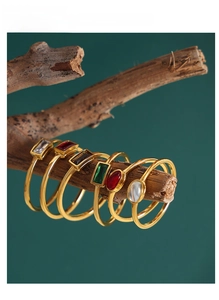 Artistic close-up of gold-plated rings with colorful gemstones on a wooden branch