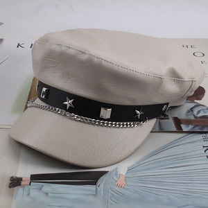 Close-up of beige faux leather baker boy hat with silver star studs and chain detail
