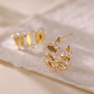 Luxurious gold C-shaped earrings with white zircon crystals shown in a close-up macro view