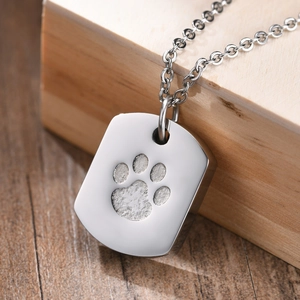 Detail of silver stainless steel urn pendant with paw print on wood background