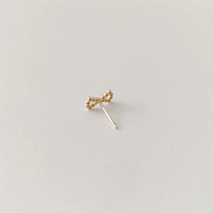 Macro shot of minimalist gold bow stud earrings with polished finish and needle closure