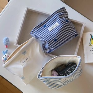 Three-piece set of blue and white striped cotton makeup bags with embroidery details