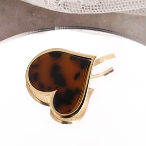 Detailed close-up of heart-shaped hair hook with amber tortoiseshell pattern inlay