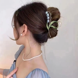 Detail of blue lily of the valley hair claw clip worn on hair with golden accents