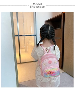 Pink mermaid toddler backpack with glitter details and shell decor on a young model