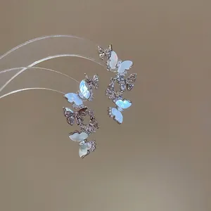 Silver butterfly earrings with mother of pearl and zircon stones on a transparent stand