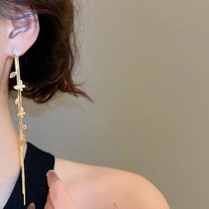 Détail de longues boucles d'oreilles papillon dorées à pampilles sur un mannequin