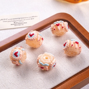 Macro detail of beige pastry-style resin beads with heart and cream patterns on a linen mat