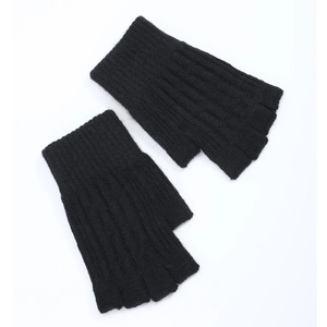 Close-up of black cable knit fingerless gloves showing ribbing texture on white backdrop