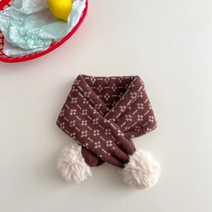 Close-up of a brown knit scarf for children with floral jacquard and white pom-poms