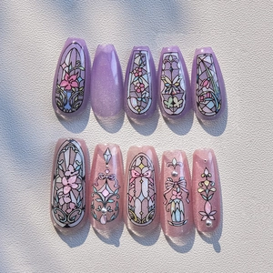 Close-up of lavender and pink cat-eye press-on nails with floral art and pearls