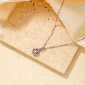 Detailed view of silver necklace featuring a pink halo pendant on silk background