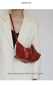 Close-up of a red oil wax leather crescent bag on a white blazer for a minimalist style