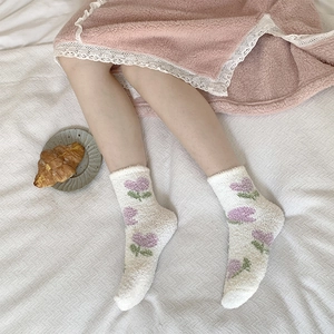 Close-up of fuzzy coral fleece socks with purple tulip pattern for winter warmth