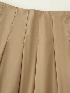 Détail d'une jupe plissée kaki avec des coutures propres et une texture lisse en polyester