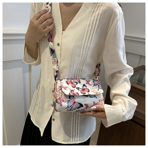 Close-up of trendy square crossbody bag with colorful butterfly prints and wide strap