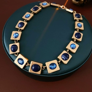 Details einer Vintage-Goldkette mit quadratischen Fassungen und blauen Kristallen