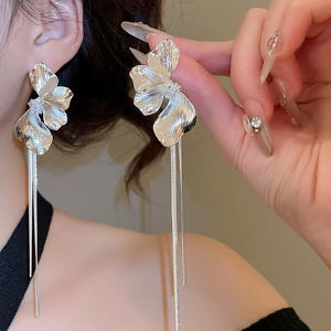 Gros plan détaillé de boucles d'oreilles fleur argentée avec longues chaînes à glands