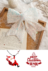 Close-up of white iridescent glitter Christmas bow ornament on rustic snowy decor