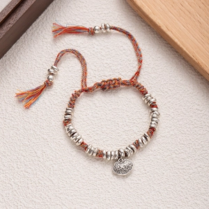 Detailed shot of handmade woven ethnic bracelet with silver charms and cloud pendant