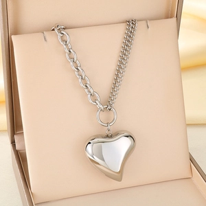 Close-up of a polished silver hollow heart pendant on a chain in a beige jewelry box