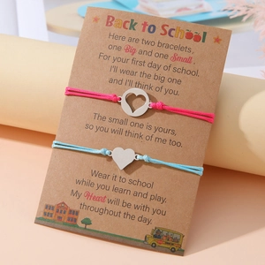 Set di braccialetti a cuore in acciaio inox con cordini rosa e blu su carta scuola