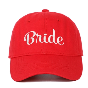 Detail showing white script Bride embroidery on a classic red cotton baseball cap