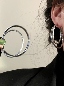 Detail of silver double hoop earrings featuring one polished and one textured glitter ring