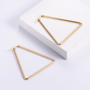 Minimalist large golden triangle hoop earrings in stainless steel on white pedestal