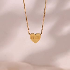 Macro detail of gold-plated heart pendant with 11:11 engraving on pink satin